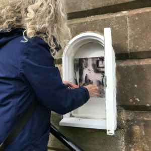 The artist installing artwork in small niche at Midsteeple, Dumfries