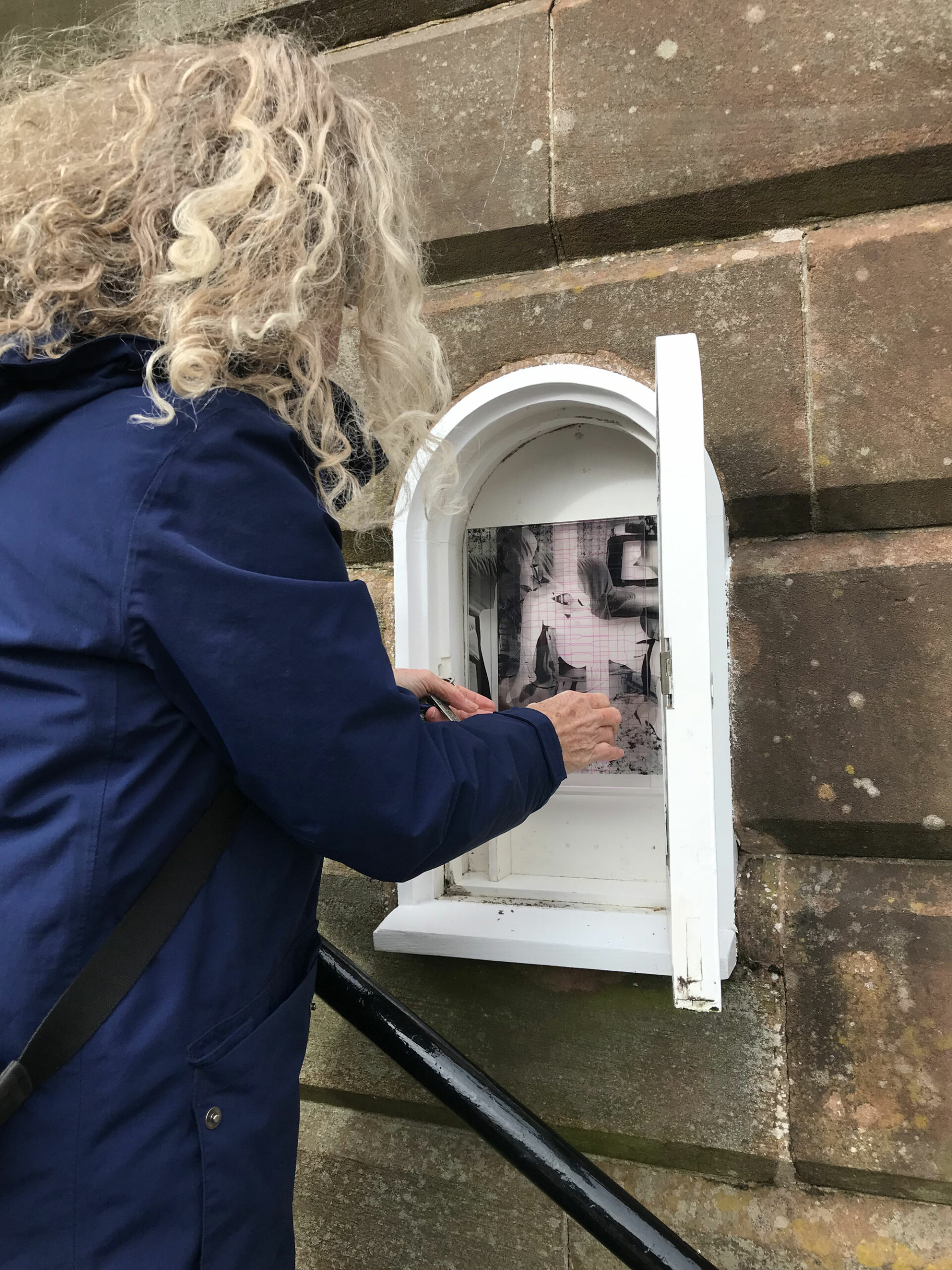 The artist installing artwork in small niche at Midsteeple, Dumfries