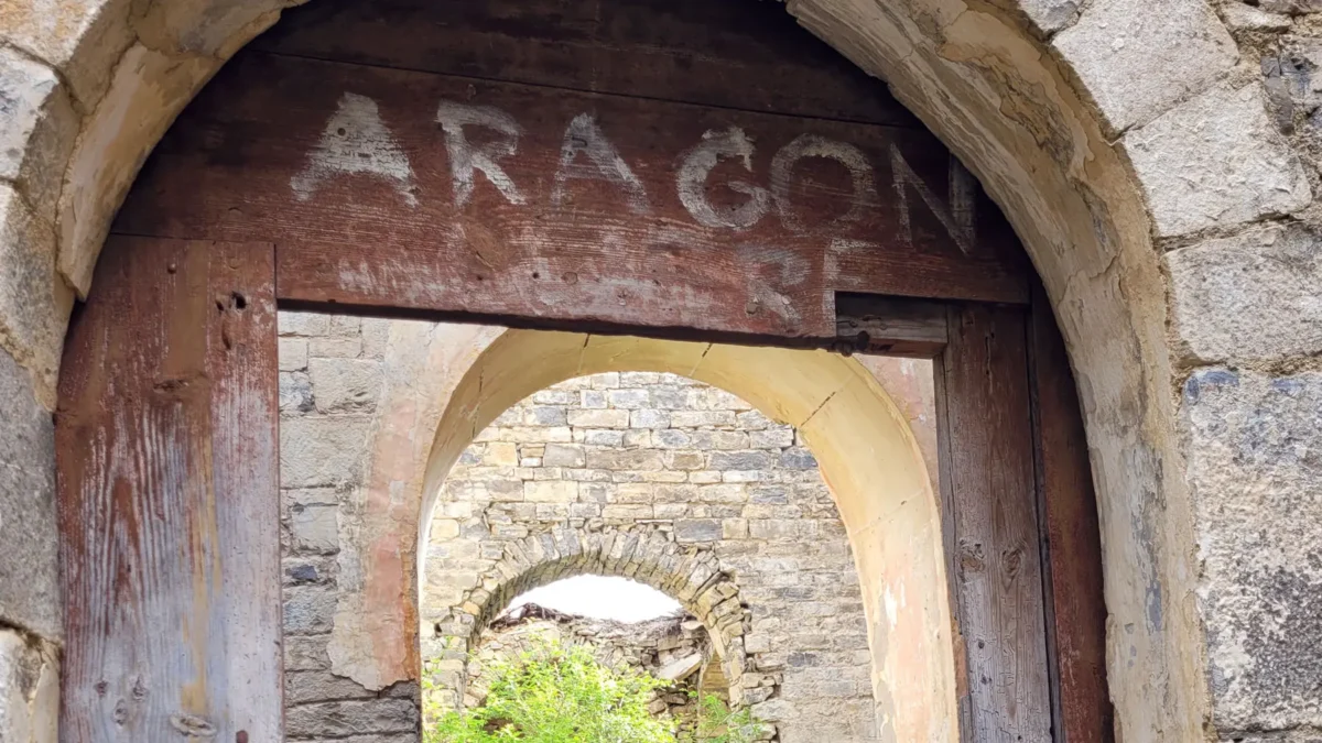 Doorway of the ruined church in Bergosa with graffiti reading “Aragon”
