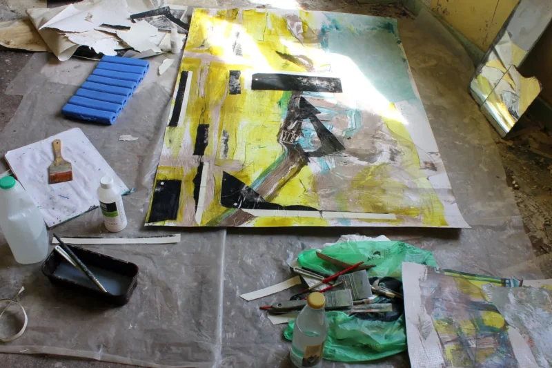 Working indoors on collage using found materials in abandoned cottages