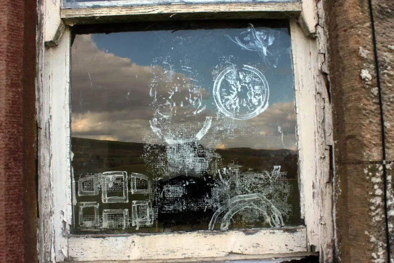 Close-up of painted image on abandoned cottage window