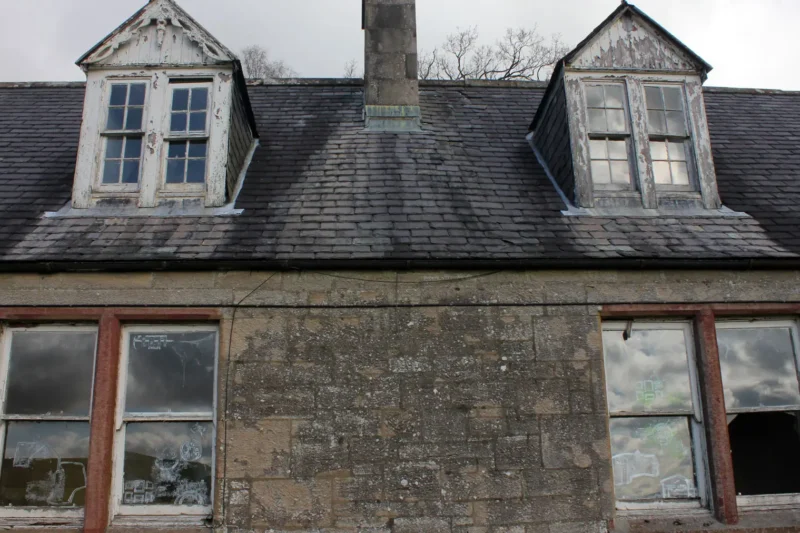 Exterior view of abandoned cottages with broken windows and window paintings