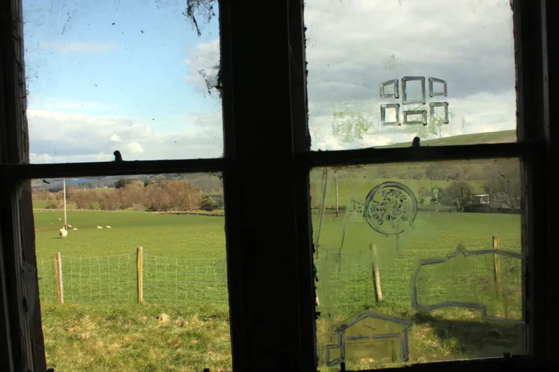 View from abandoned cottage window with painted images on glass