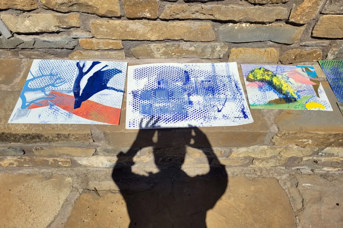 Shadow of Michele Marcoux over paintings in progress outdoors in Spain